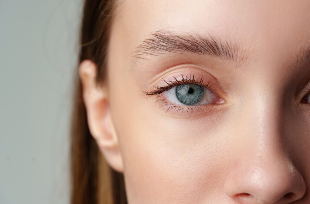 Close-up of a person’s blue-green eye with visible lashes and natural skin texture around the eyelid and brow area.