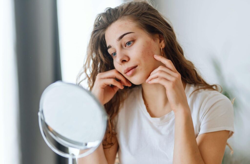 A person is struggling with Rosacea and looking at herself in the mirror.